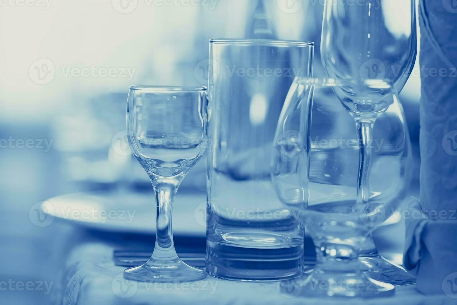 Glass goblets on the restaurant table tinted in blue. photo
