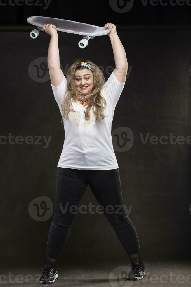 A beautiful fat woman wants to throw a skateboard on the floor. The girl is a plus size model. photo