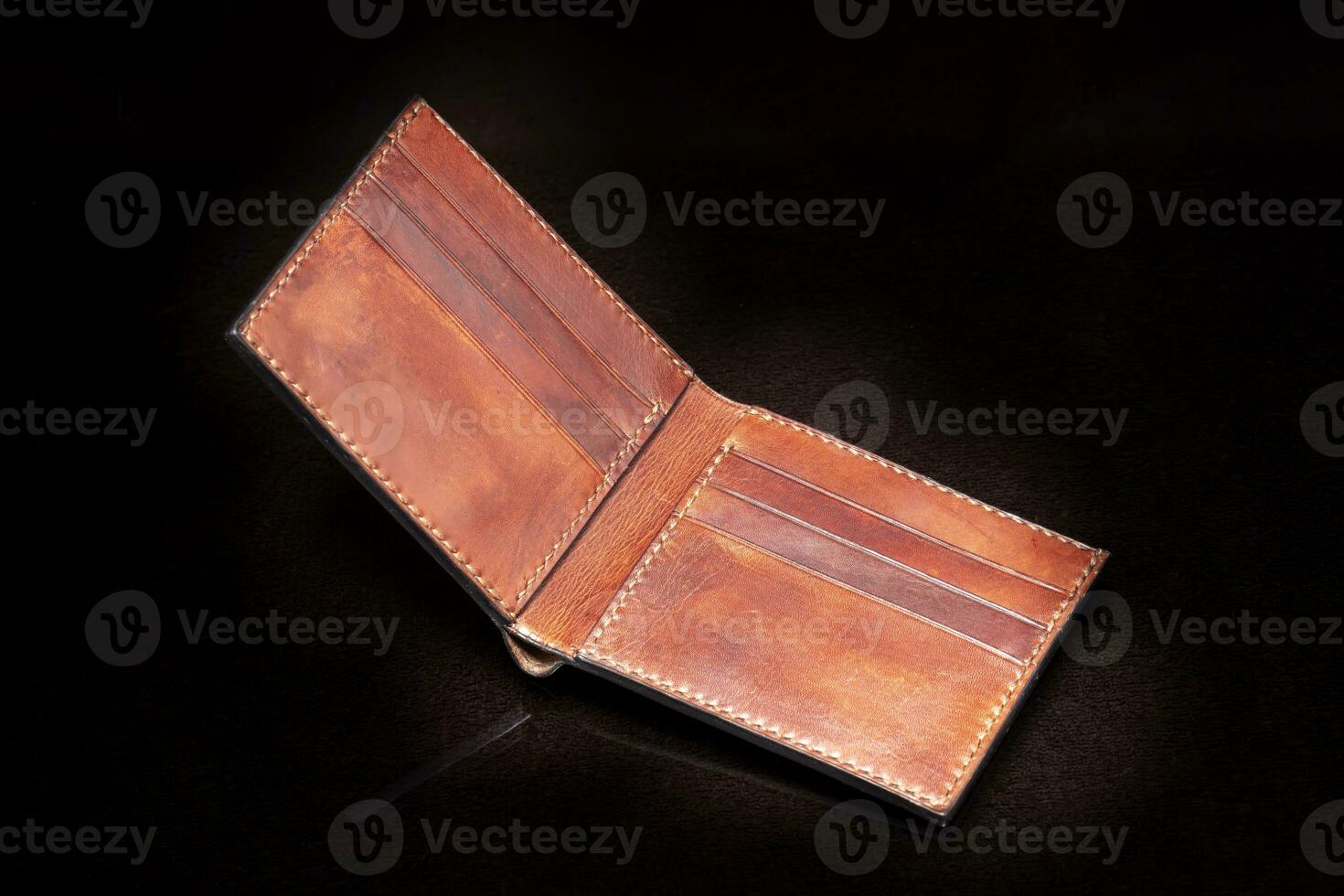 Open leather brown purse with pockets on a dark background. photo