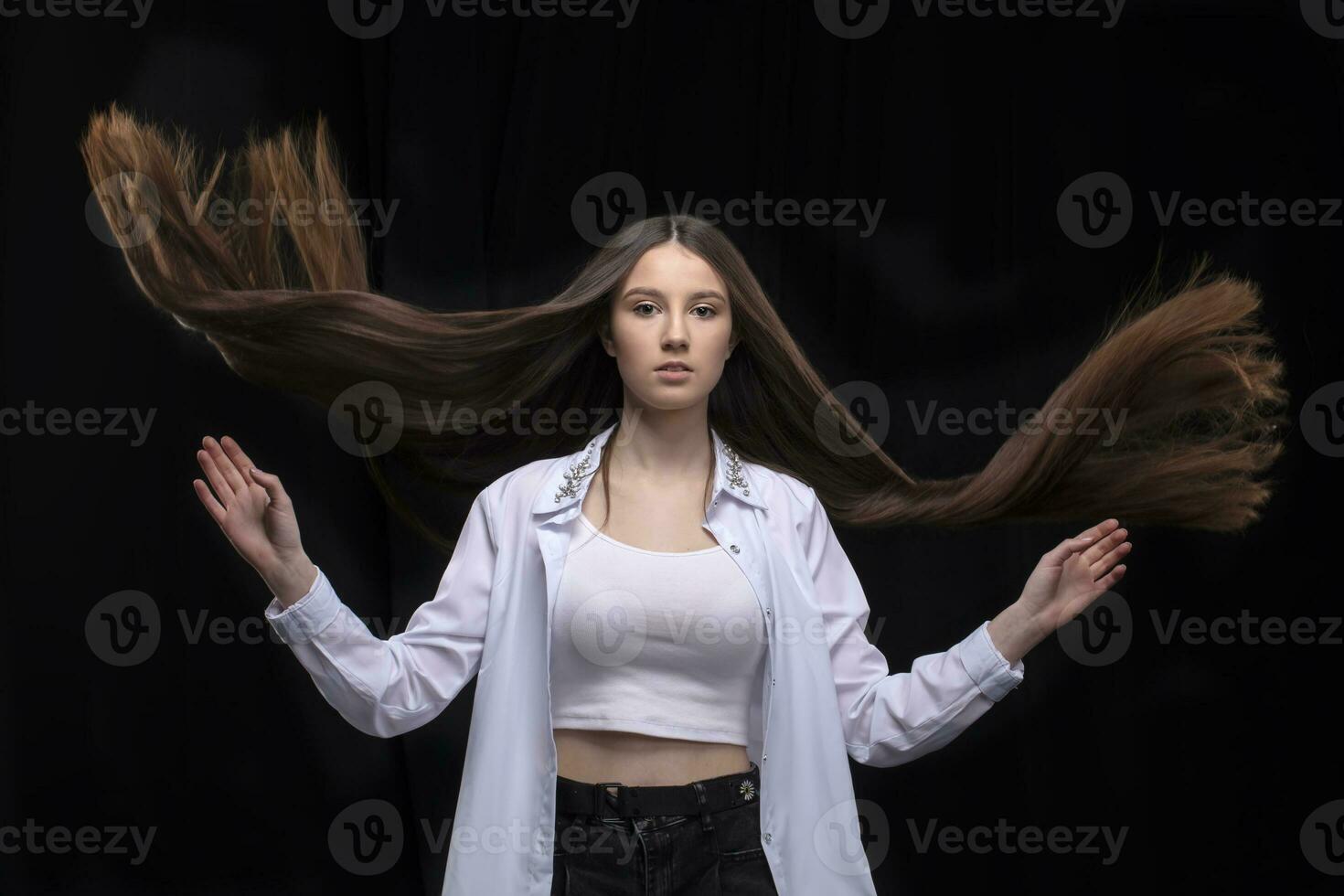 Beautiful brunette with long flying hair on a dark background. photo