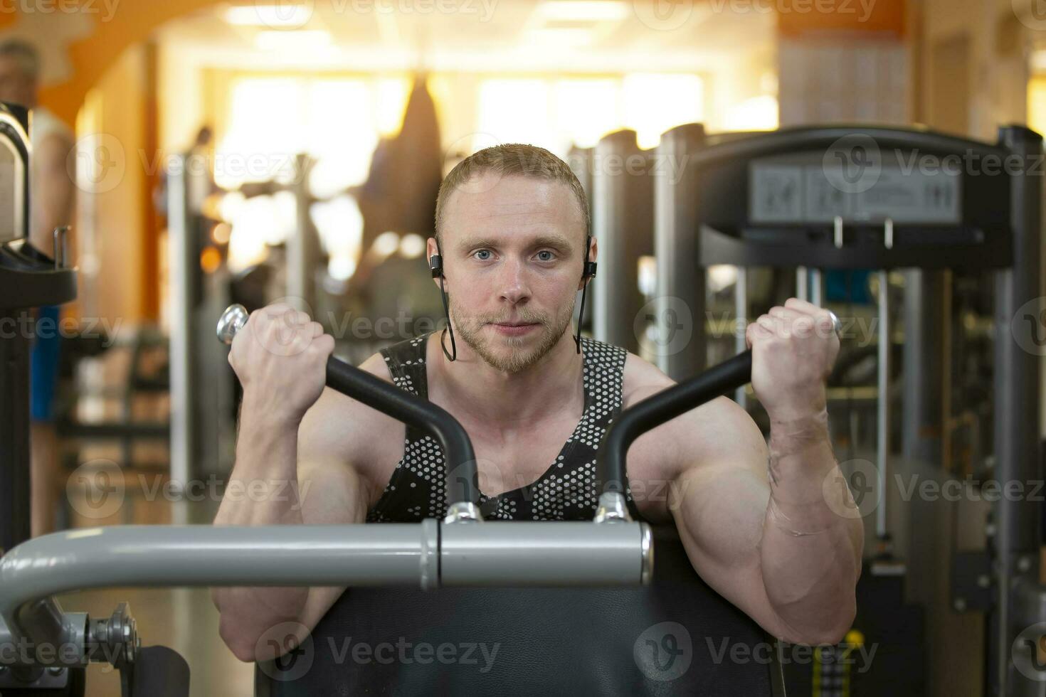 A handsome young strong man of an athletic physique is engaged on a sports simulator. photo