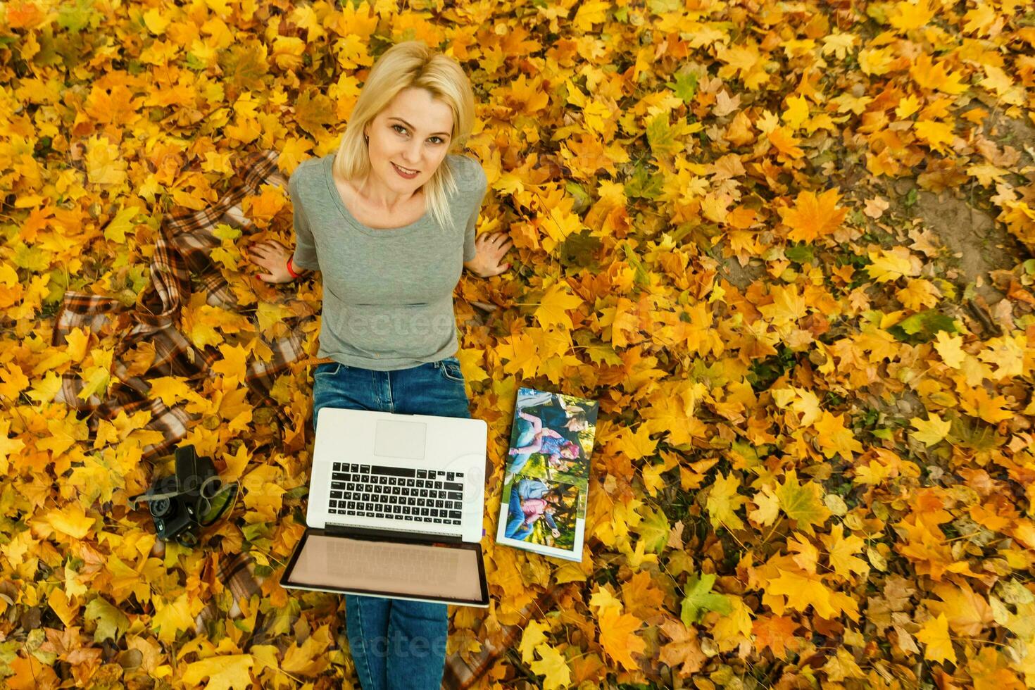 mujer con ordenador portátil y foto libro en otoño parque