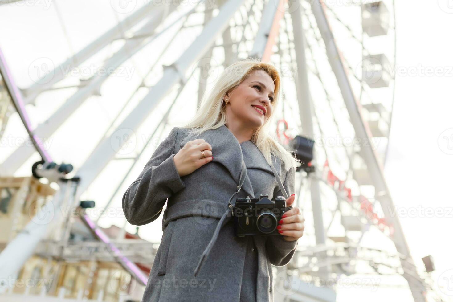 Young woman walking outdoors on the city street near ferris wheel smiling cheerful. photo