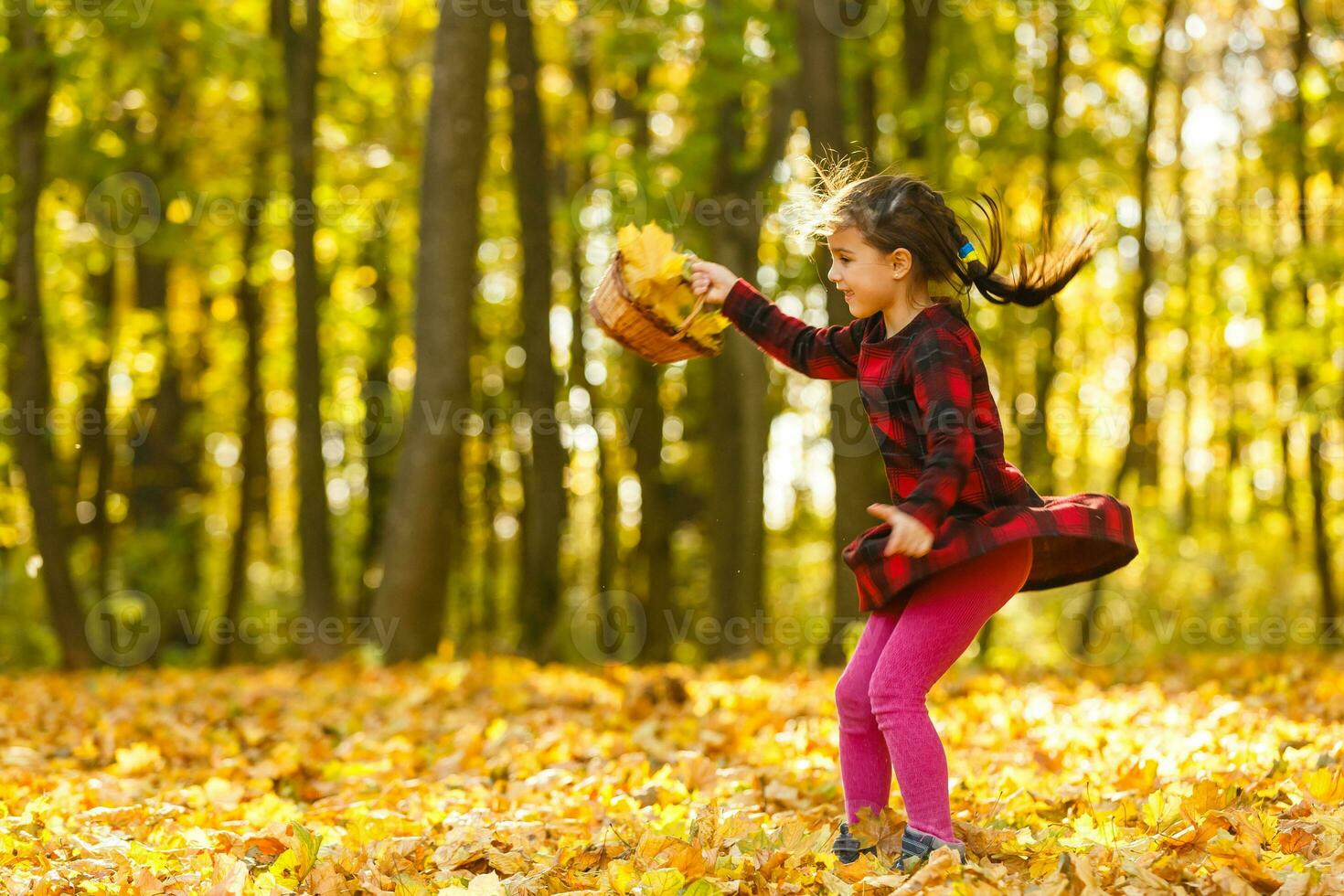 Very cheerful child having fun while tossing up yellow leaves photo