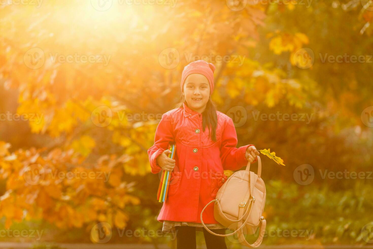 alumno de primario colegio con libro en mano. niña con mochila cerca edificio al aire libre. comenzando de lecciones primero día de caer. foto