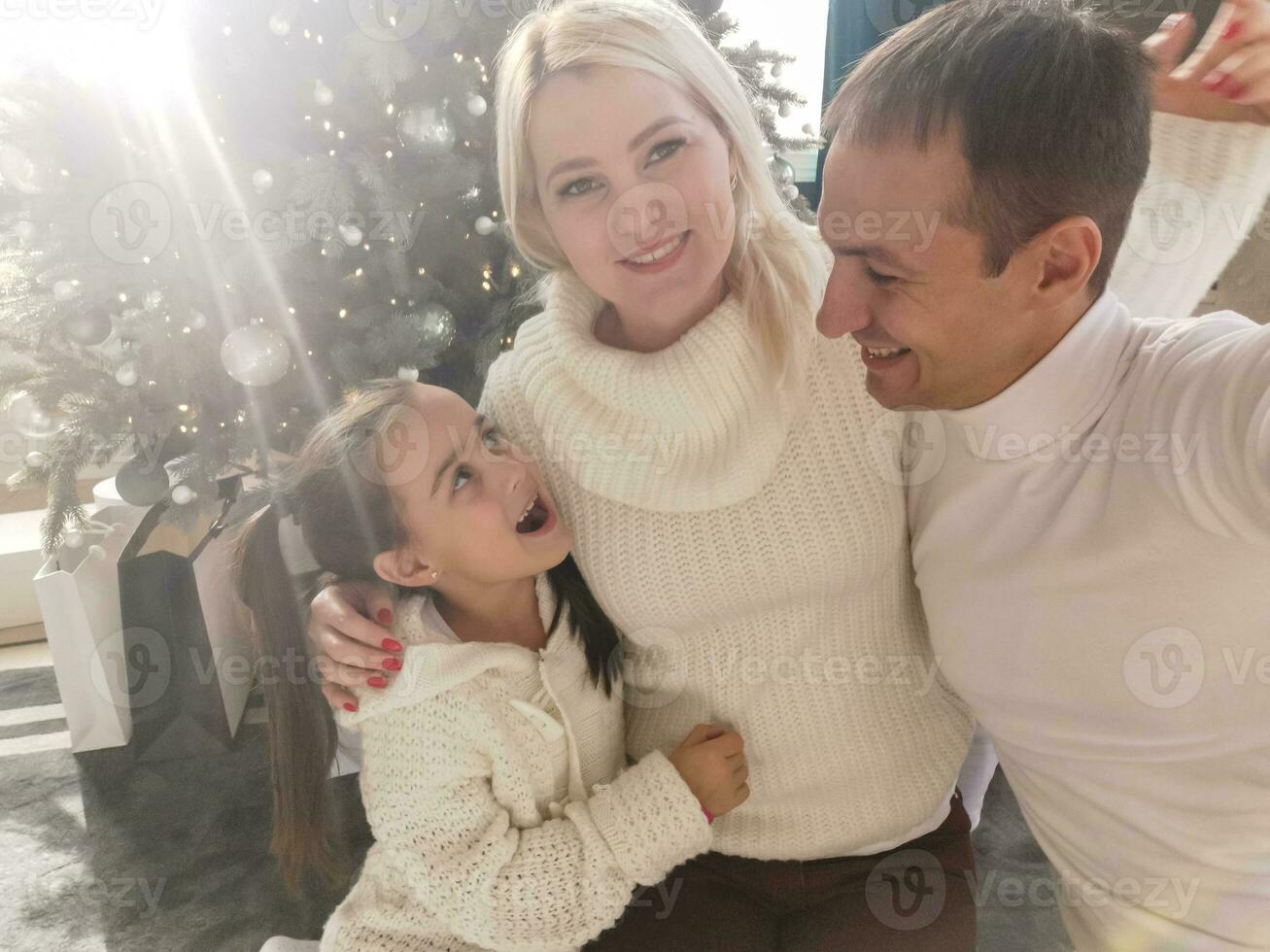 familia, vacaciones, tecnología y personas - sonriente madre, padre y pequeño niña haciendo selfie con cámara terminado vivo habitación y Navidad árbol antecedentes foto