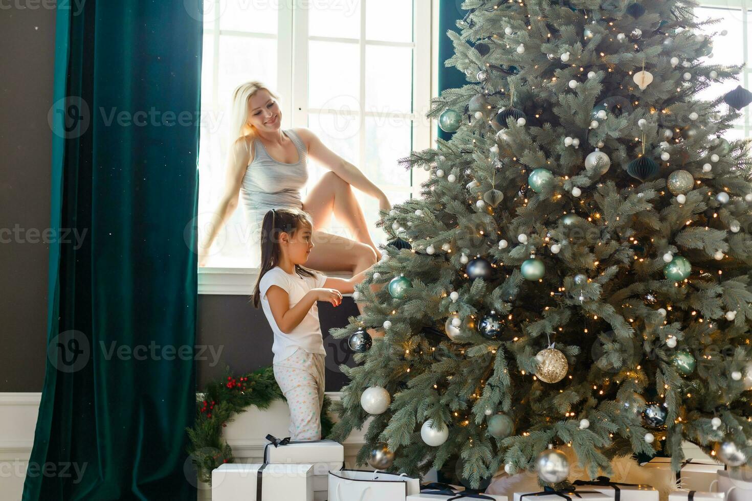 Happy family mother and child girl near a Christmas tree with Christmas present photo