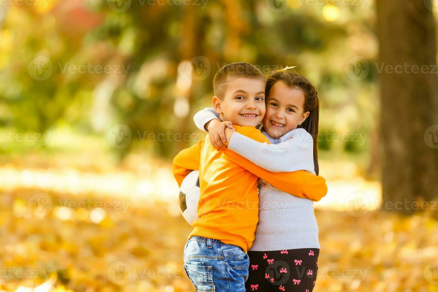 Children playing with autumn fallen leaves in park photo