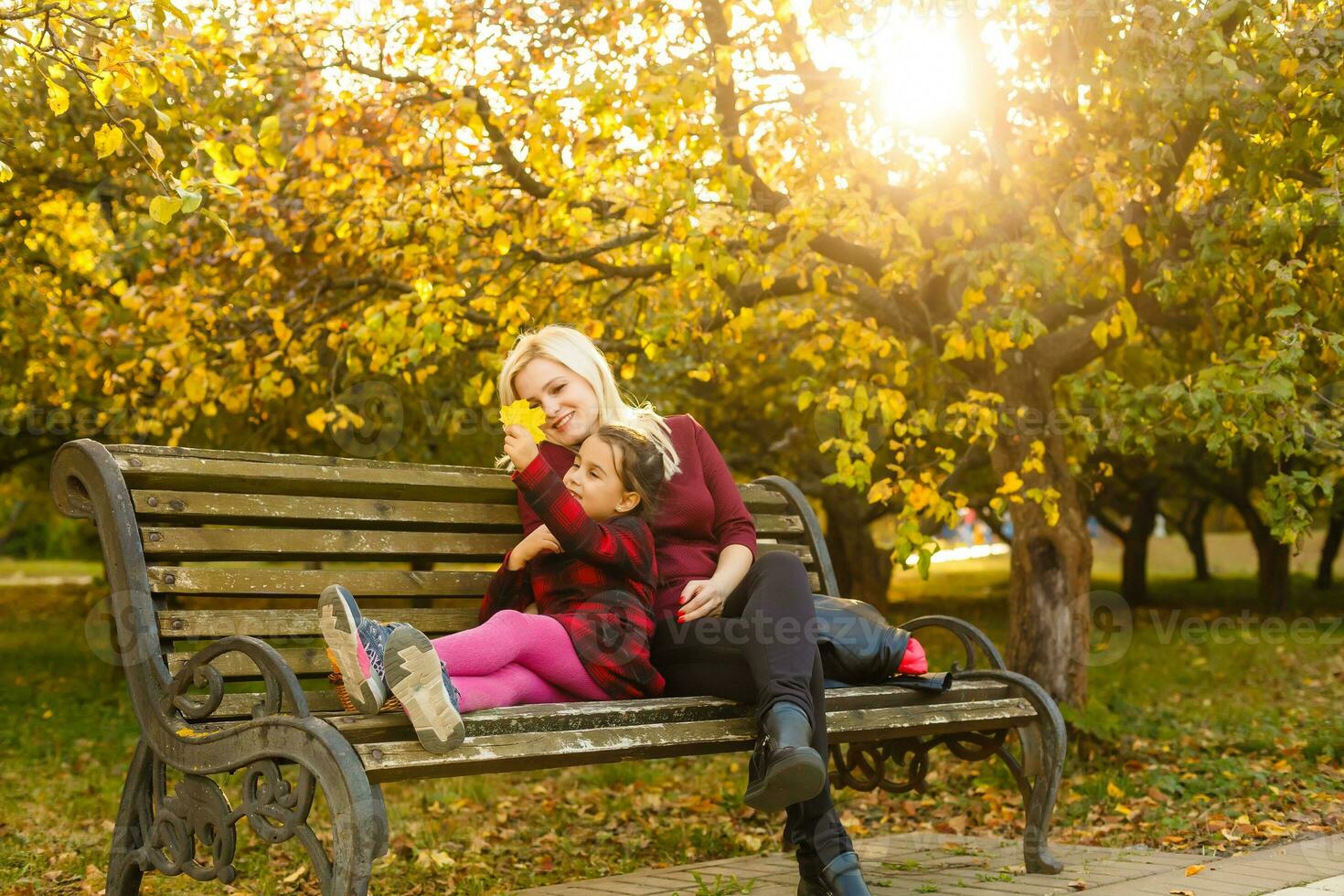 mother and daughter on a bench in autumn park photo