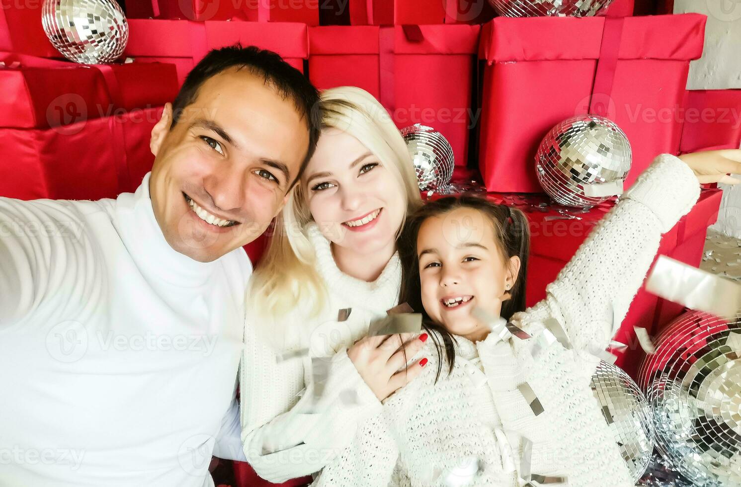 Christmas. Family. Technology. View on the smartphone. Dad, mom and daughter looking at camera and smiling while doing selfie photo