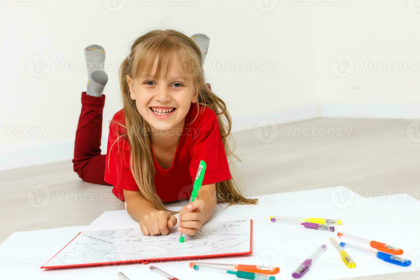 contento pequeño niña practicando leyendo tendido en el piso en su habitación foto