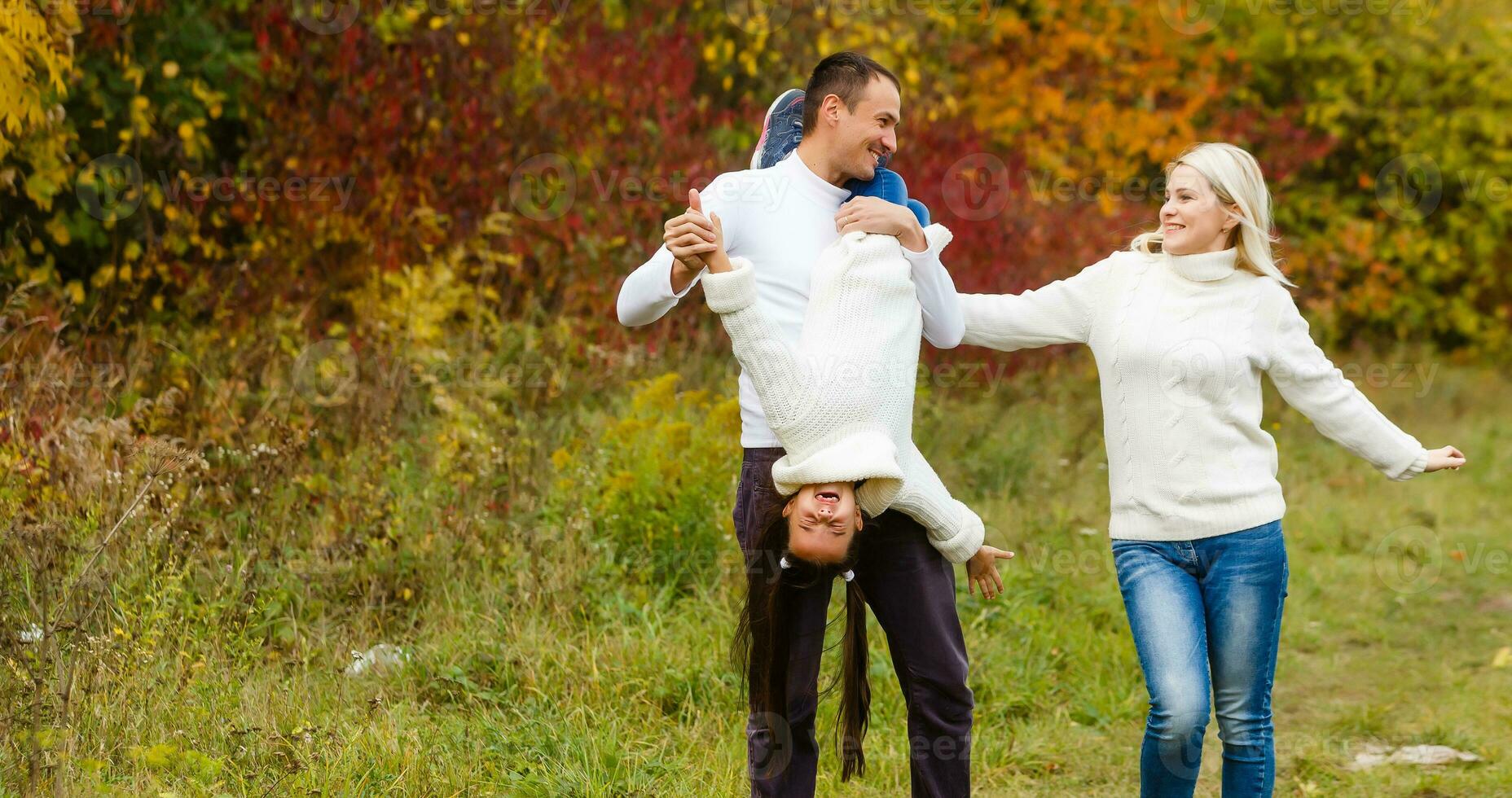 imagen de encantador familia en otoño parque, joven padres con bonito adorable hija jugando al aire libre, tener divertido en patio interior en caer, contento familia disfrutar otoñal naturaleza foto