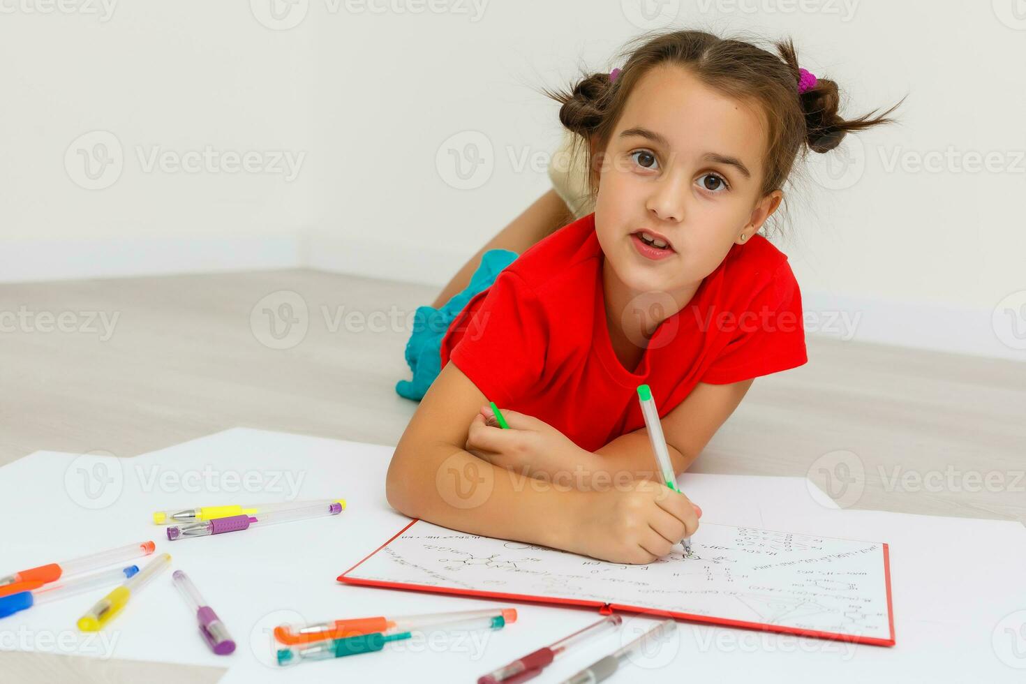 Education at home concept - Cute little girl studying with pile of books on the floor at home. Isolated over white background photo