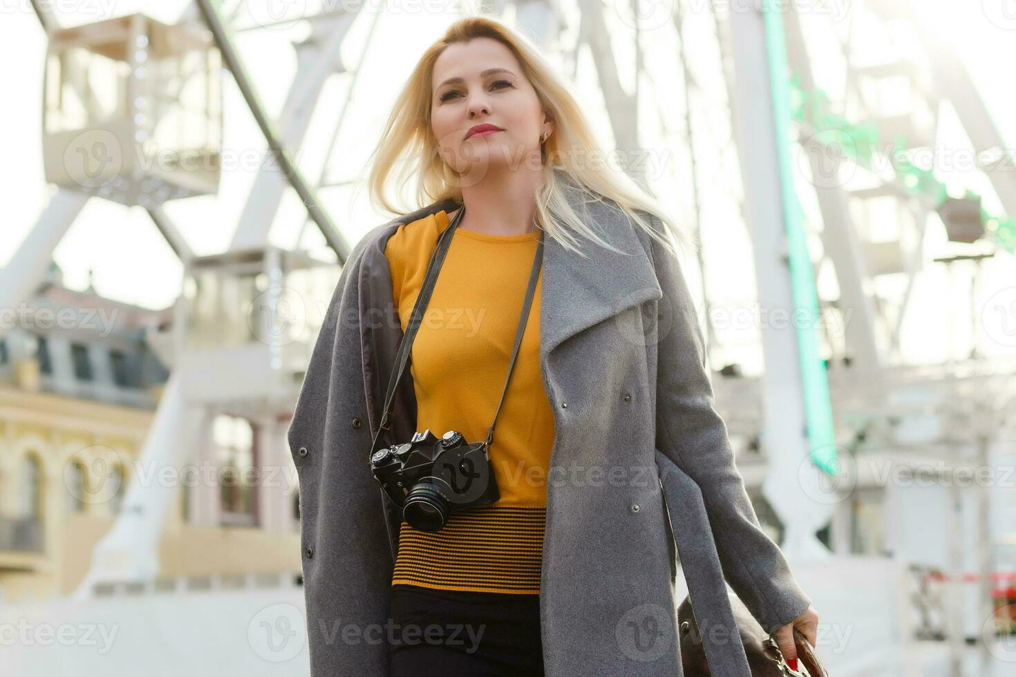 The young girl walks around the city near sights. Ferris wheel. Amusement park. autumn photo