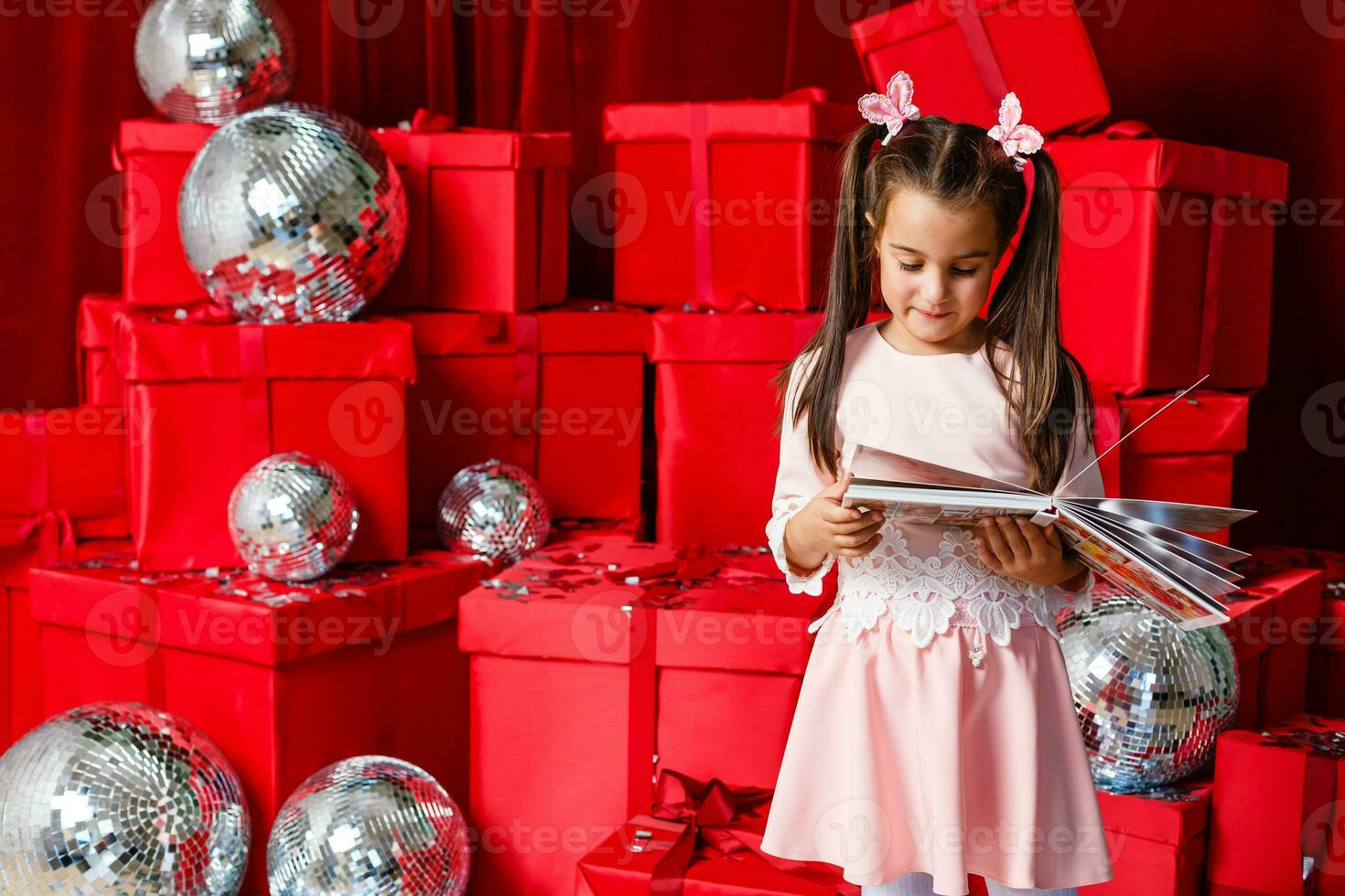 little girl looking photobook in front of Christmas tree photo