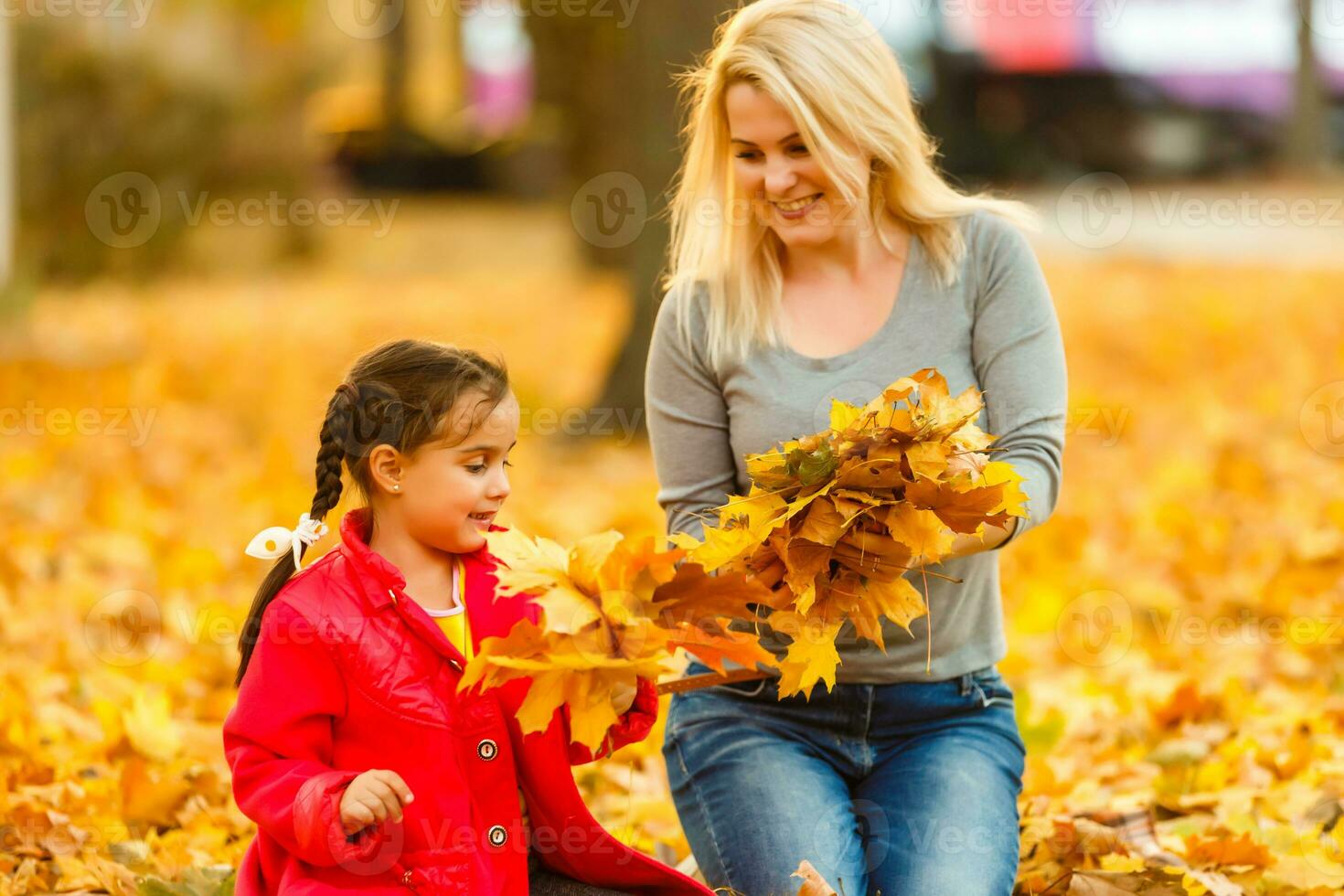 Happy parent and kid holding autumn yellow leaves outdoor. photo