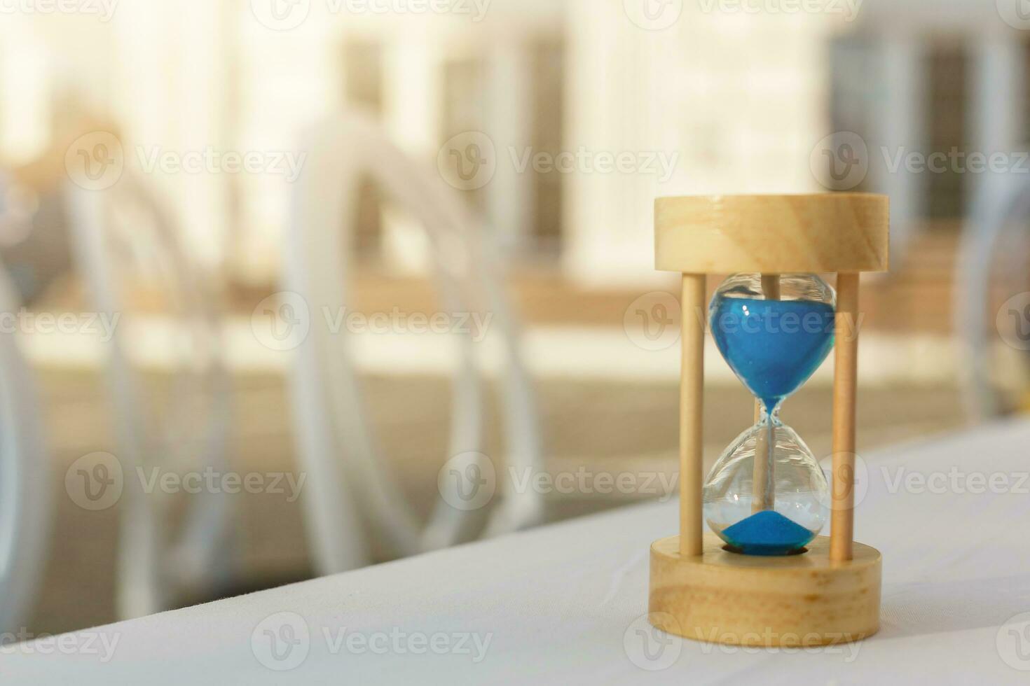 Wood hourglass or sandglass with home. Invertible device with two connected glass bulbs containing sand that takes an hour to pass from upper to lower bulb. Concept for business deadline times photo