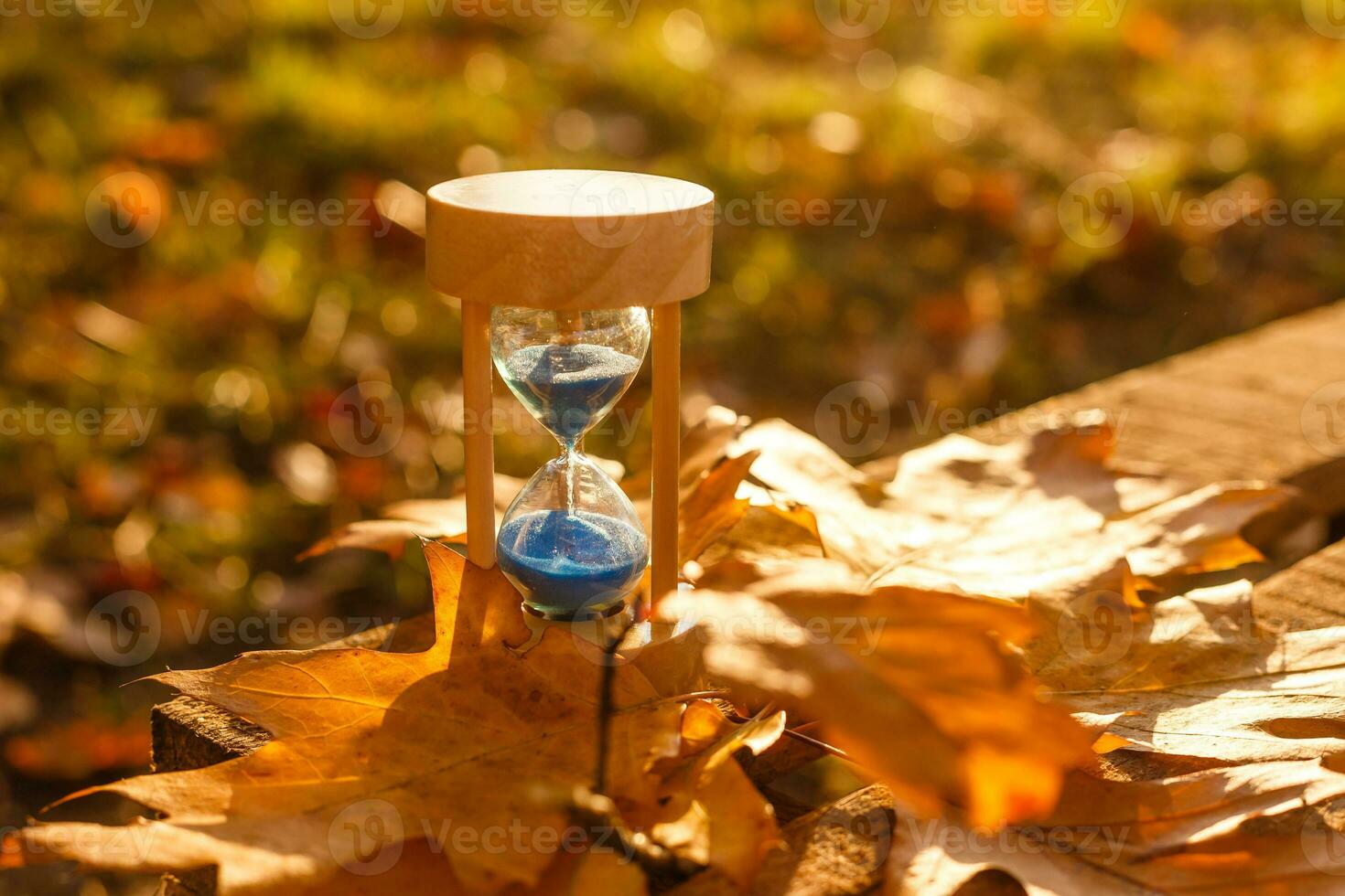 Autumn time theme, Sandglass on fallen leaves in various colors with copy space. photo