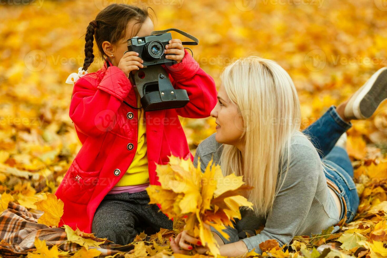 Young mother playing with her daughter in autumn park photo