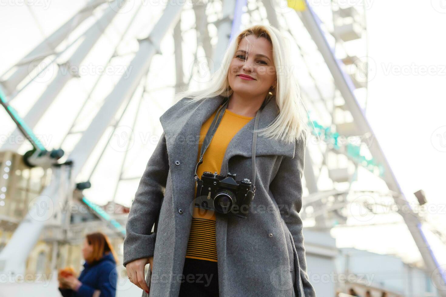 The young girl walks around the city near sights. Ferris wheel. Amusement park. autumn photo