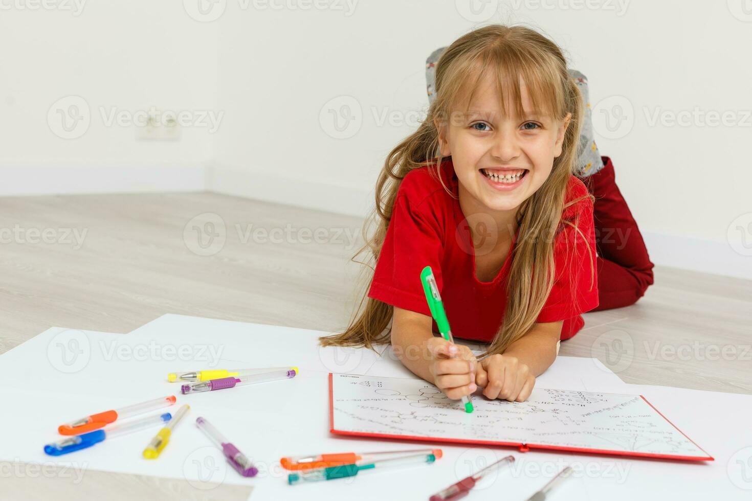 Education at home concept - Cute little girl studying with pile of books on the floor at home. Isolated over white background photo