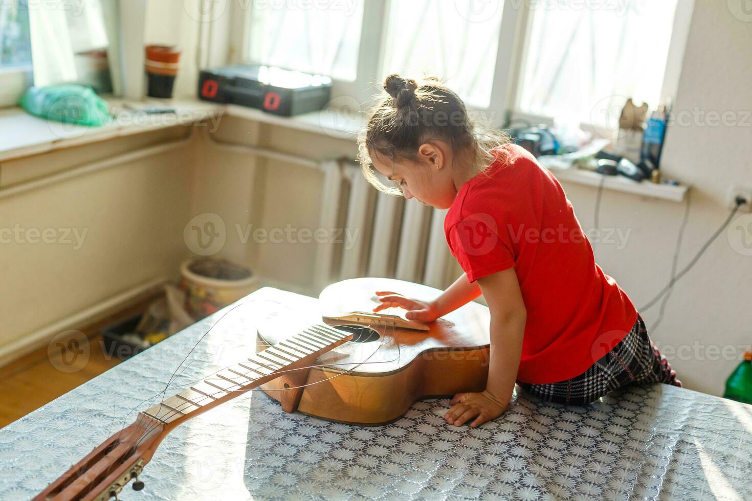little girl holding a broken guitar, guitar repair photo