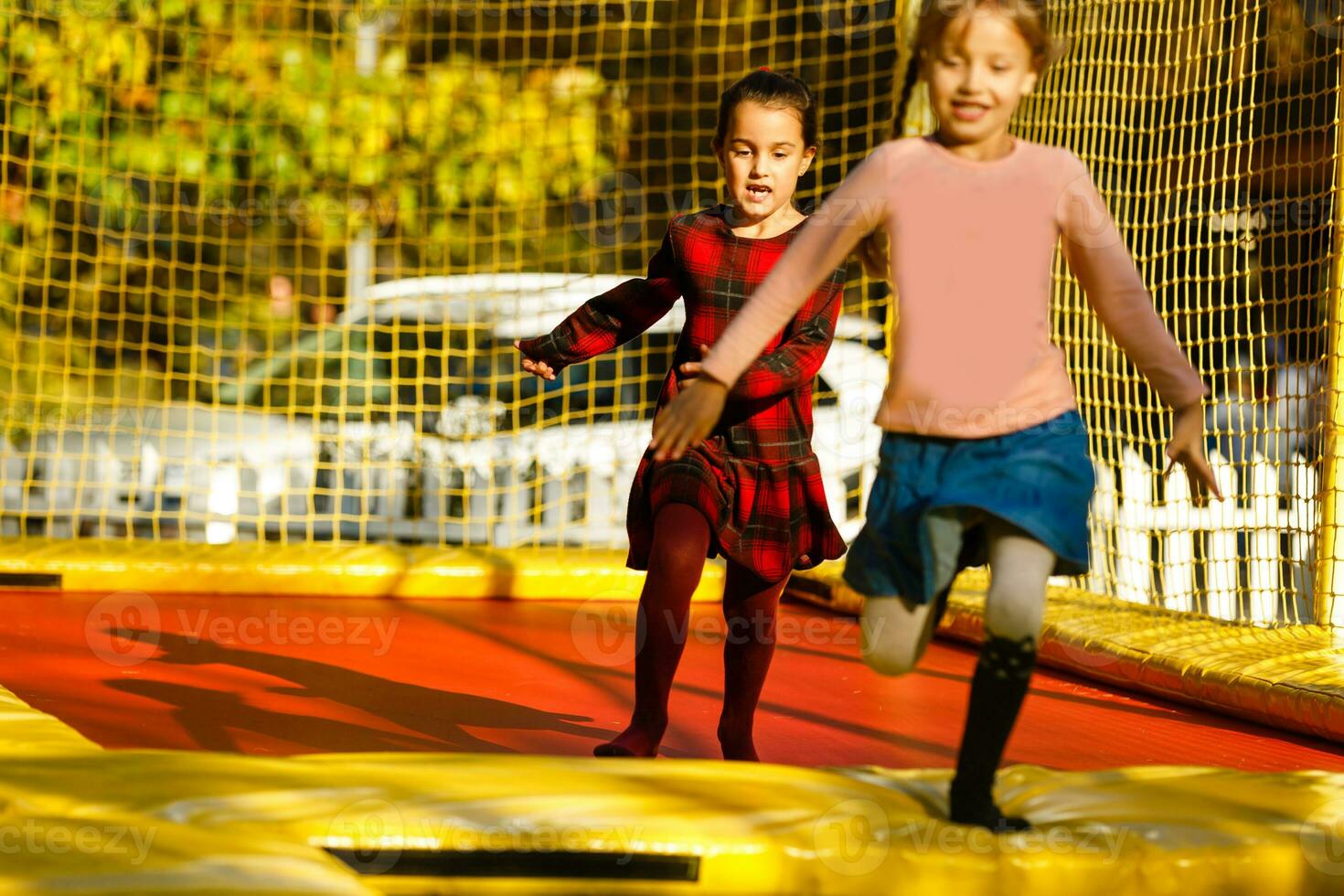 two little girls jumping on a trampoline at an autumn fair photo