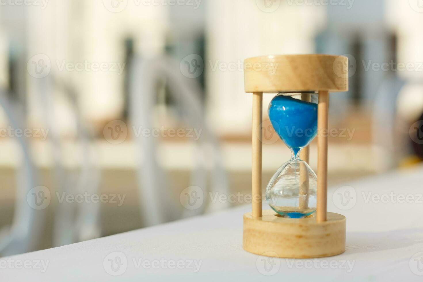 Sand passing through the glass bulbs of an hourglass measuring the passing time as it counts down to a deadline or closure on a yellow background with copyspace photo
