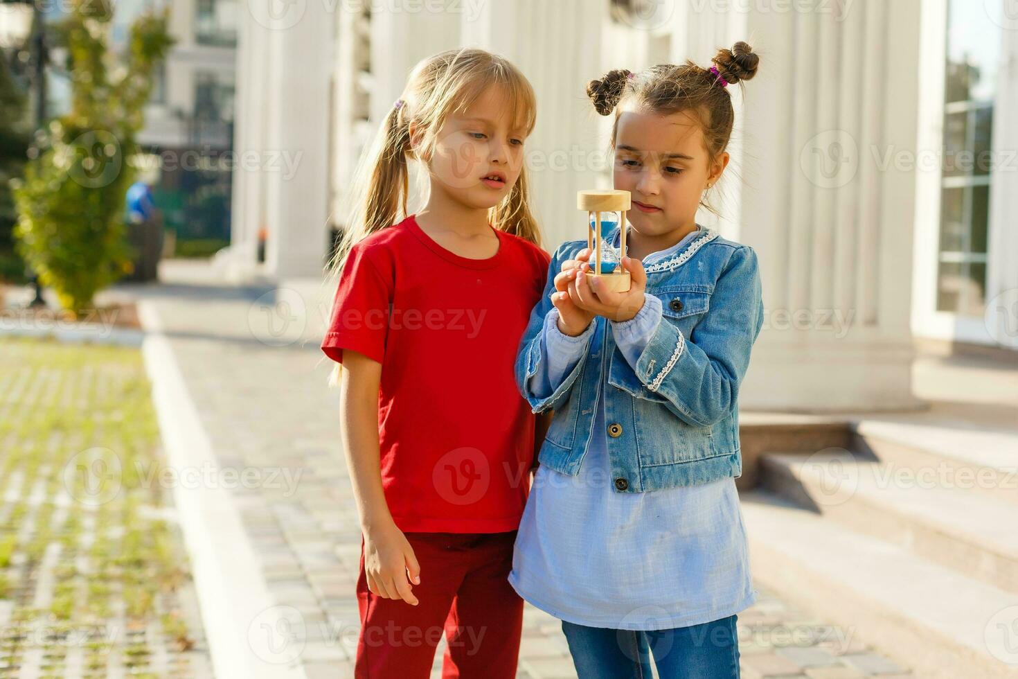 two little girls holding an hourglass and smiling photo