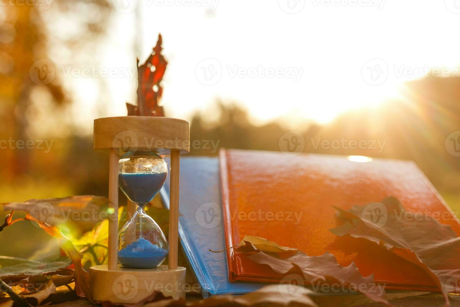Autumn time theme, Sandglass on fallen leaves in various colors with copy space. photo
