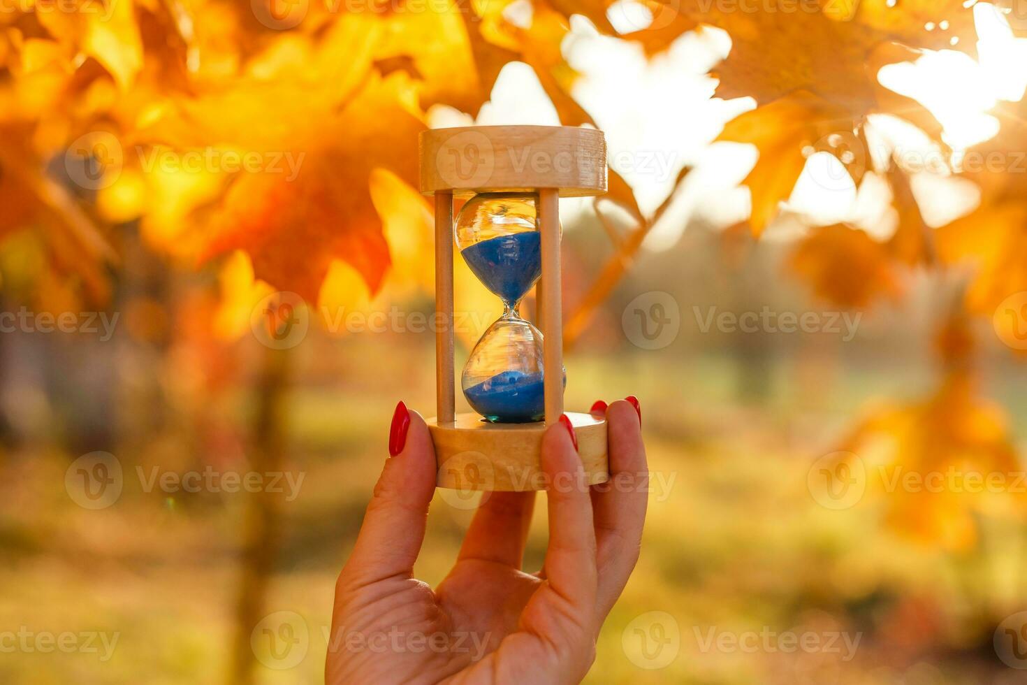 Autumn time theme, Sandglass on fallen leaves in various colors with copy space. photo