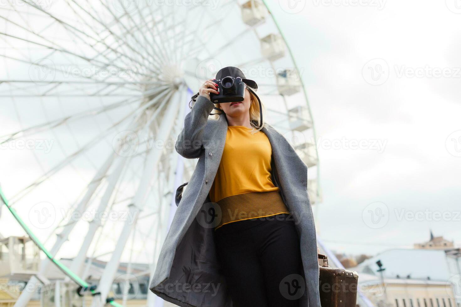 The young girl walks around the city near sights. Ferris wheel. Amusement park. autumn photo