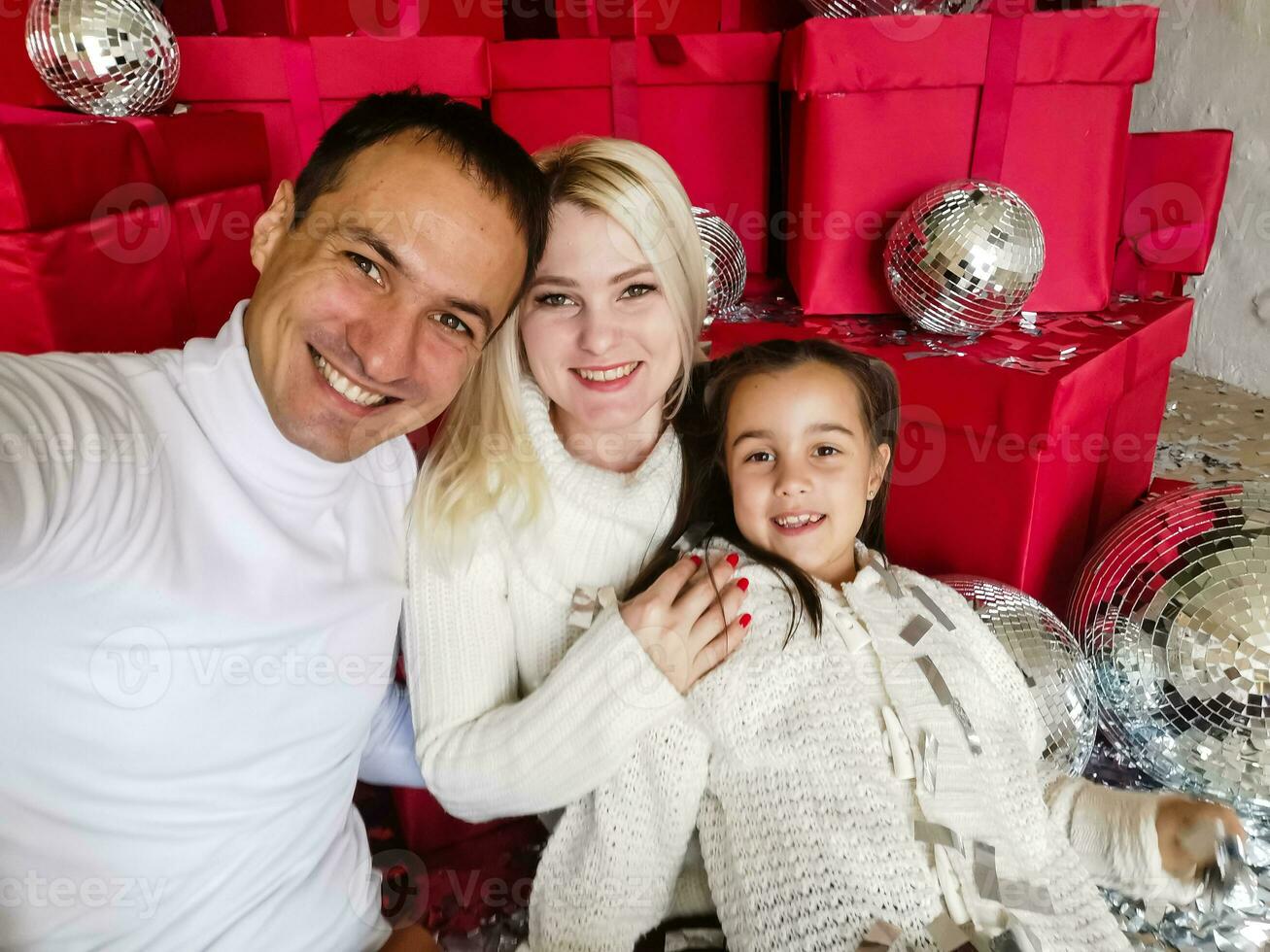 familia, vacaciones, tecnología y personas - sonriente madre, padre y pequeño niña haciendo selfie con cámara terminado vivo habitación y Navidad árbol antecedentes foto