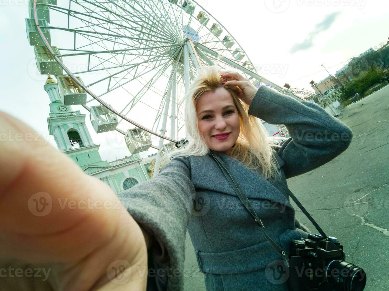 The young girl walks around the city near sights. Ferris wheel. Amusement park. autumn photo