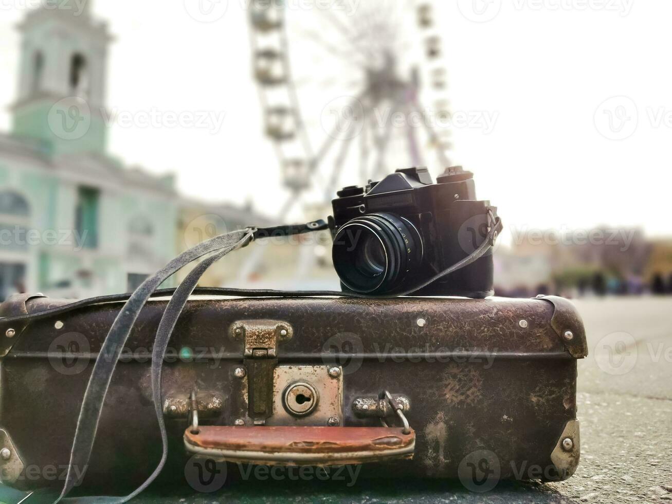 old camera and suitcase against the background of the ferris wheel photo