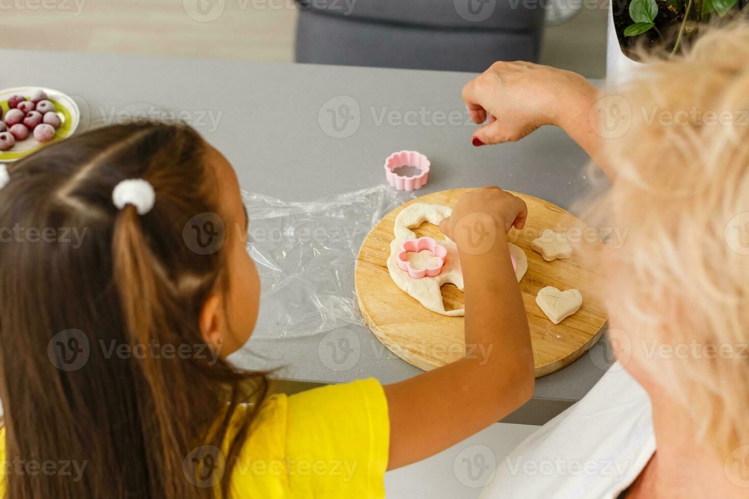 linda pequeño niña y su abuela hacer galletas en cocina. foto