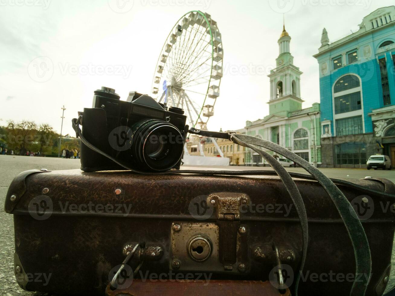 old camera and suitcase against the background of the ferris wheel photo