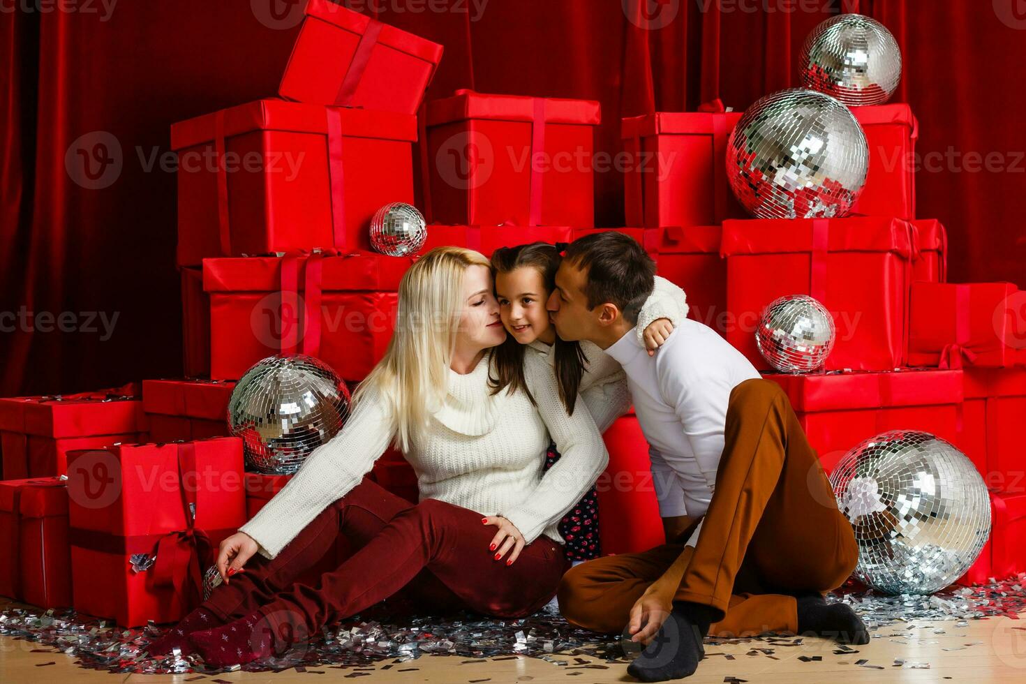 Happy parents kissing daughter and giving xmas present on bed photo