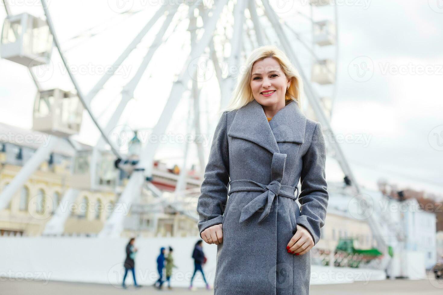 Young woman walking outdoors on the city street near ferris wheel smiling cheerful. photo