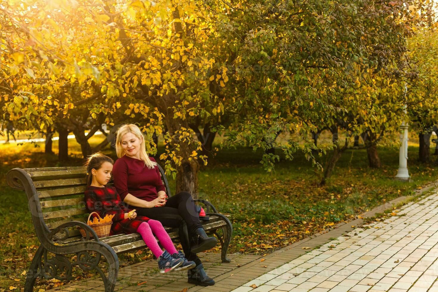 Happy mother and daughter embracing on a bench in an autumn park photo