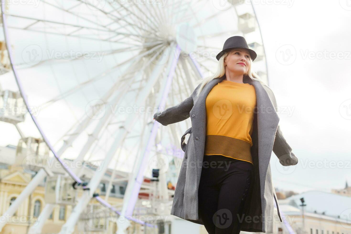 The young girl walks around the city near sights. Ferris wheel. Amusement park. autumn photo