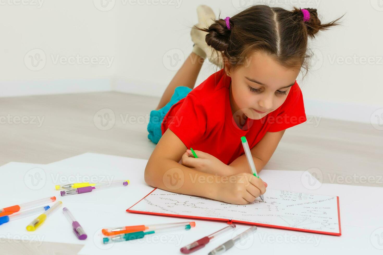 Happy little girl practicing reading laying on the floor in her room photo