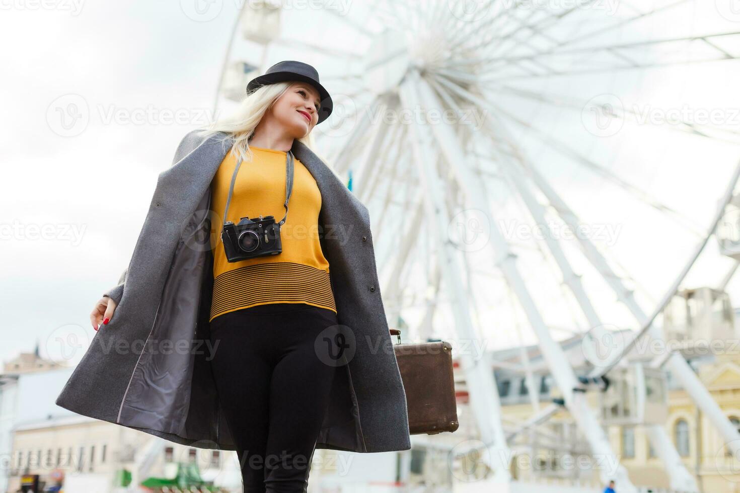 The young girl walks around the city near sights. Ferris wheel. Amusement park. autumn photo