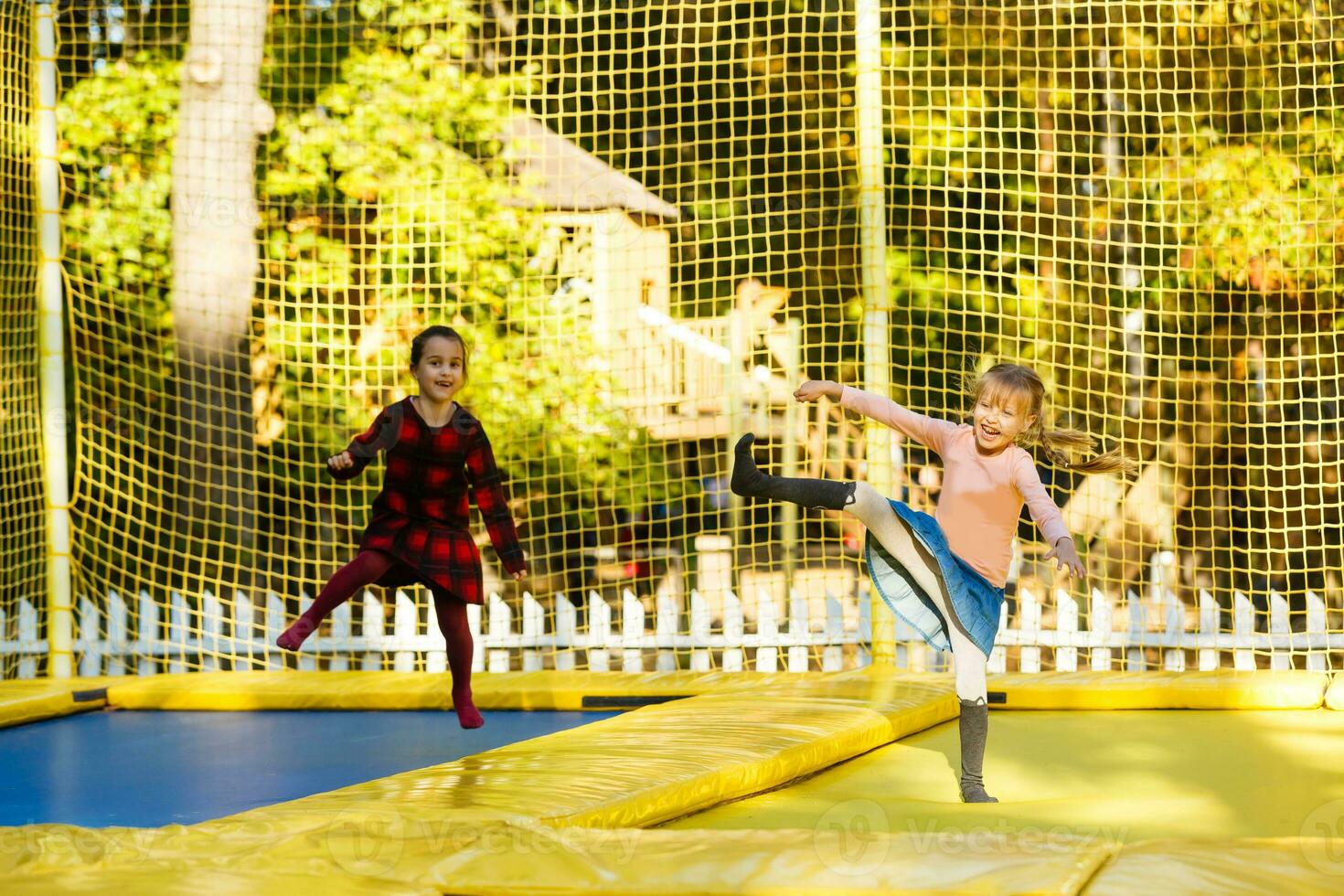 two little girls jumping on a trampoline at an autumn fair photo