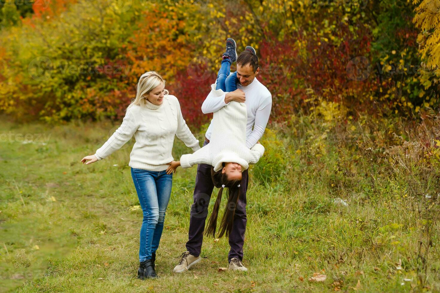 imagen de encantador familia en otoño parque, joven padres con bonito adorable hija jugando al aire libre, tener divertido en patio interior en caer, contento familia disfrutar otoñal naturaleza foto