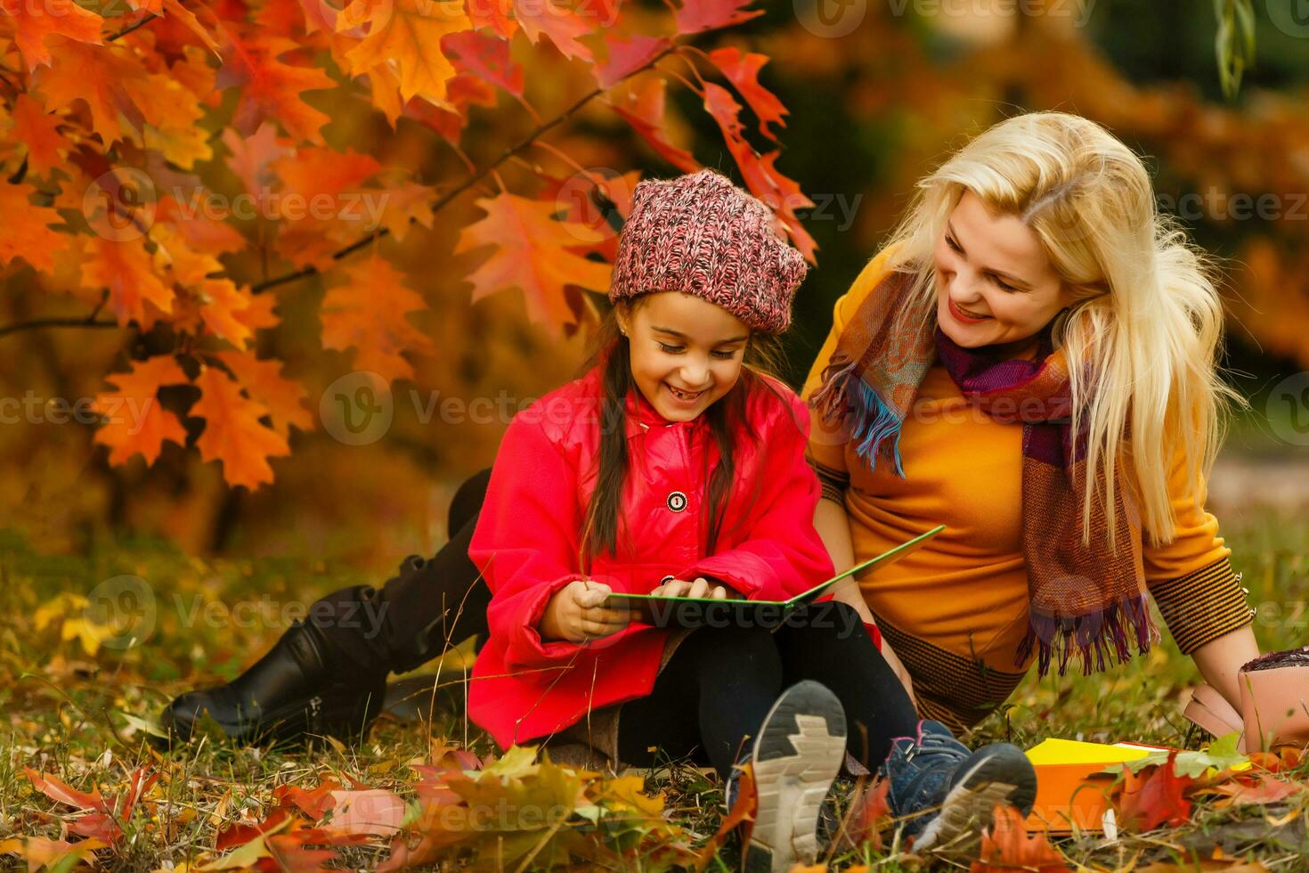 young beautiful mother and her little daughter in the autumn park photo