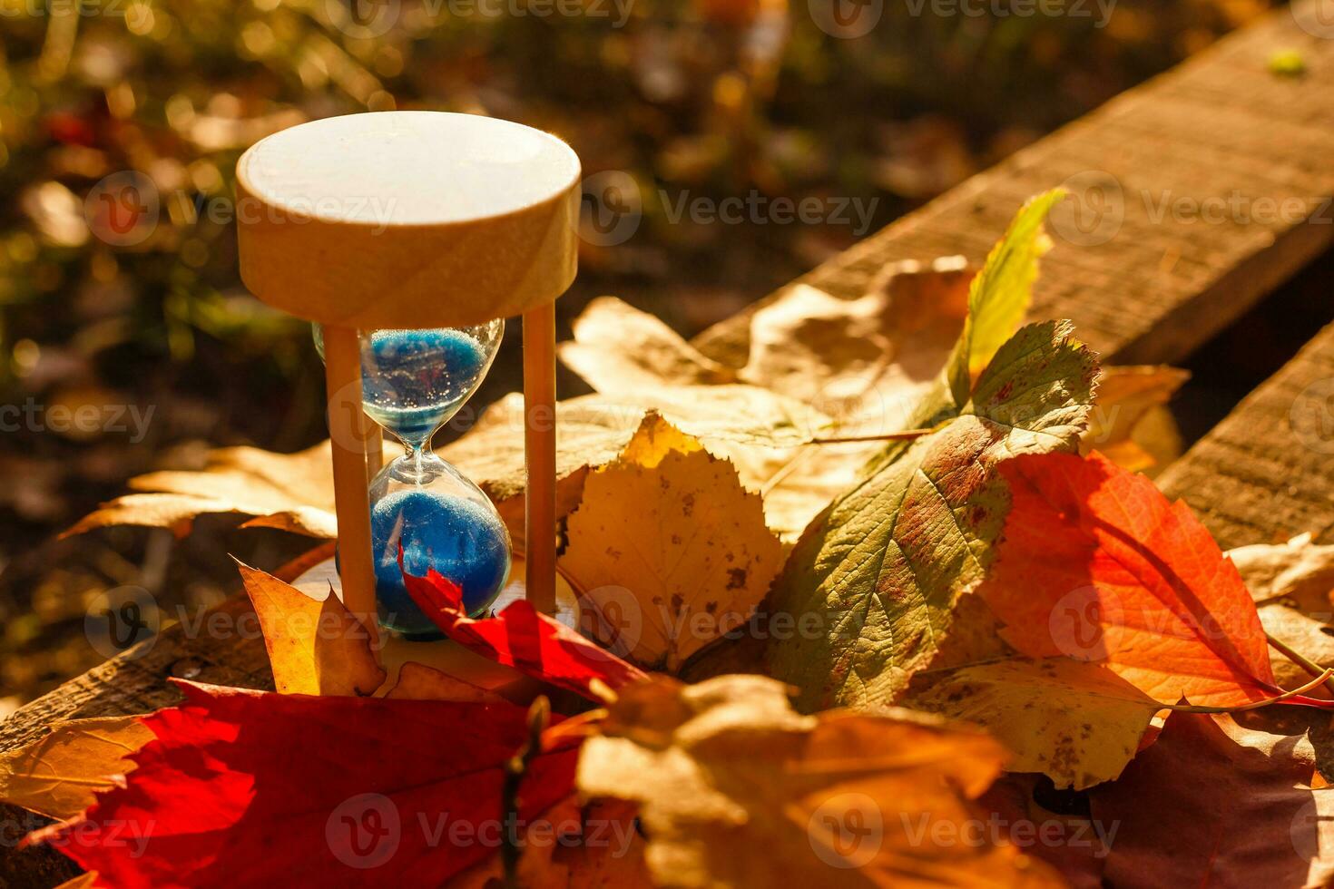 Autumn time theme, Sandglass on fallen leaves in various colors with copy space. photo