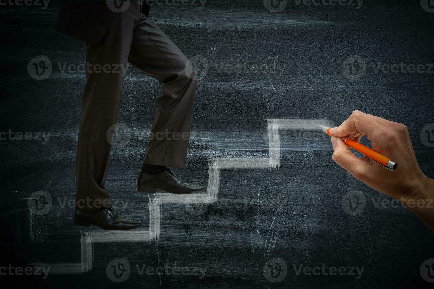 Businessman climbing the career stairs drawn on a chalkboard with copy space photo