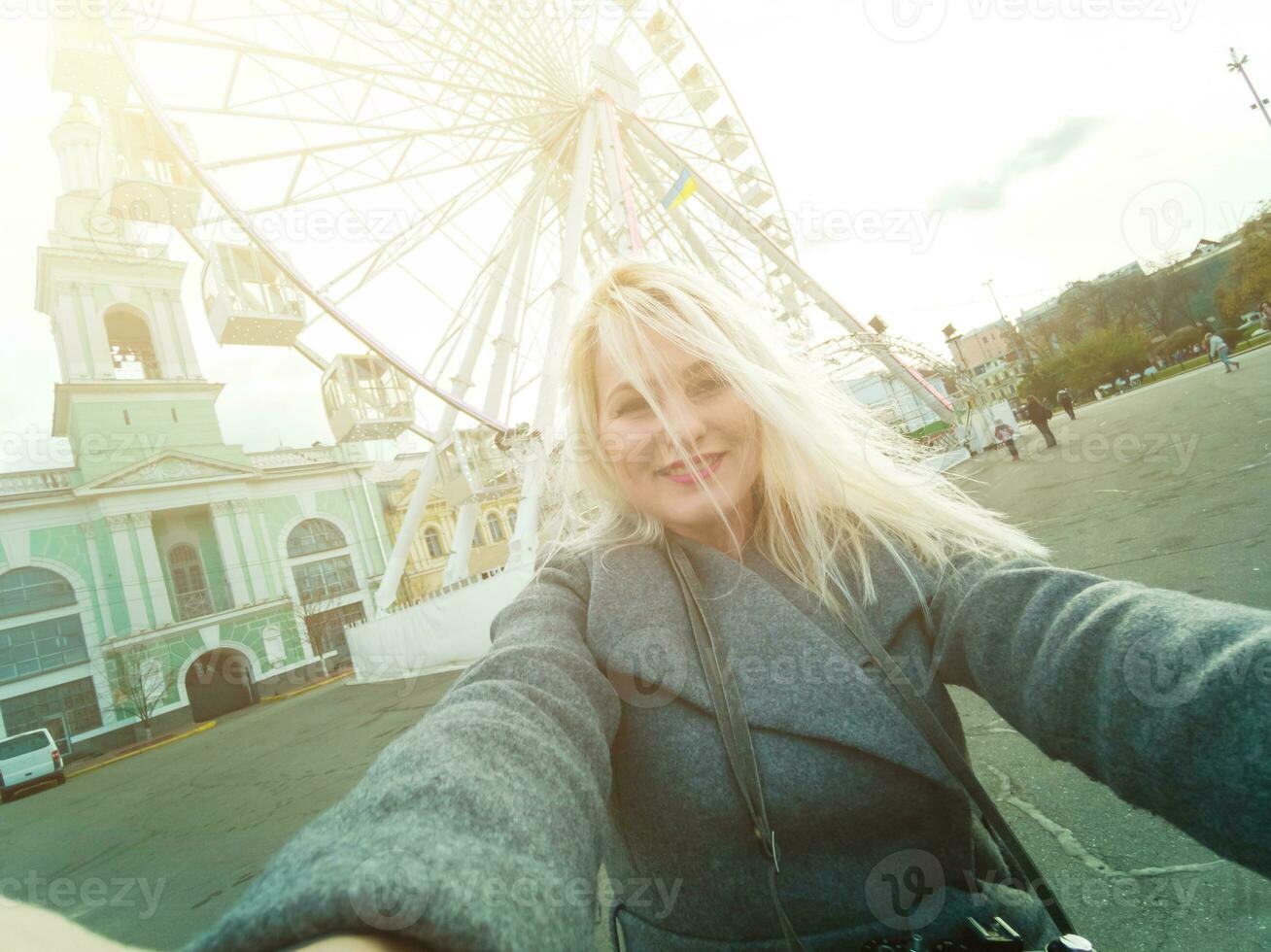 The young girl walks around the city near sights. Ferris wheel. Amusement park. autumn photo