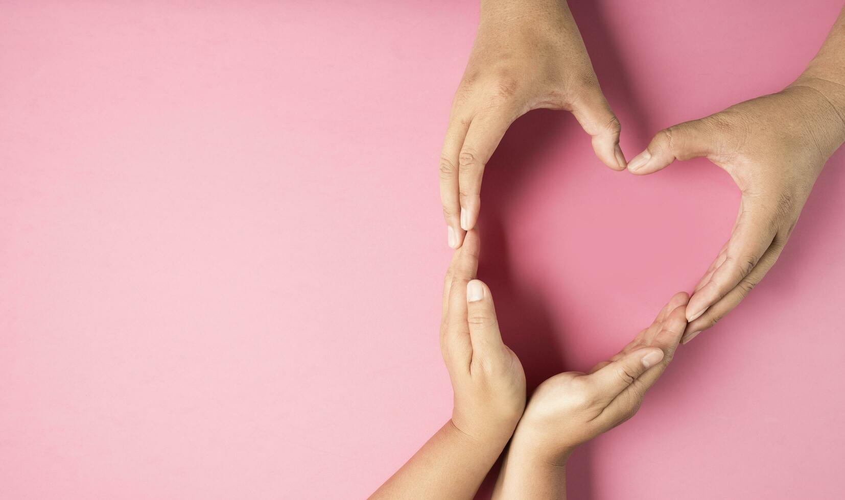 adulto manos hecho corazón símbolo en rosado antecedentes , salud cuidado, Organo donación, familia vida seguro, mundo corazón día, mundo salud día, Orando concepto foto